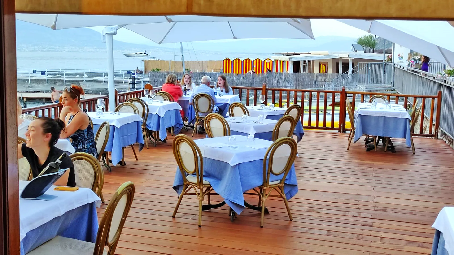 Tavoli sulla terrazza in legno affacciata sul mare di Marina d’Equa